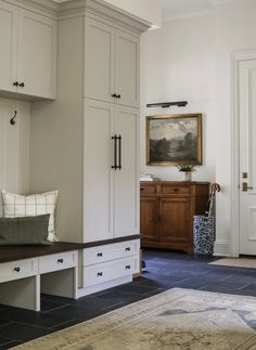 an entryway with white cabinets and drawers