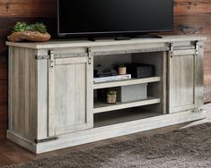 an entertainment center with a flat screen tv on it's stand in front of a wooden wall