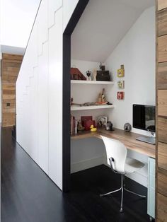 a room with a desk, computer and shelves on the wall next to each other