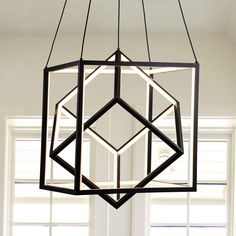 a black and white geometric light fixture hanging from a ceiling in a room with windows