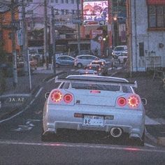 the back end of a white car parked in front of a building on a city street