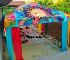 a colorful gazebo sitting on top of a patio next to a wooden fence and trees