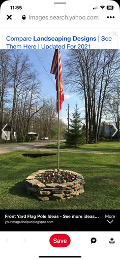 an image of a flag pole in the middle of a field with flowers and trees