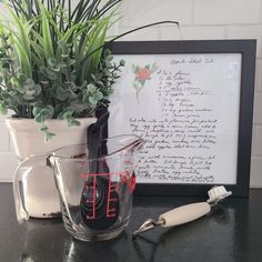 a glass mug with writing on the side next to a brush and potted plant