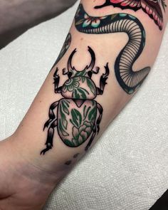 a tattoo on the arm of a person with a scarp and an insect in it