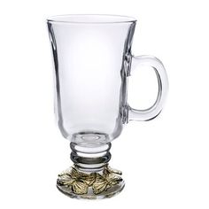 a clear glass cup with gold leaves on the rim and bottom is sitting in front of a white background