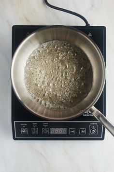 a frying pan filled with food sitting on top of a stove next to a digital scale