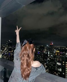 a woman standing on top of a tall building with her arms up in the air