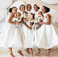 a group of women standing next to each other wearing white dresses and holding bouquets