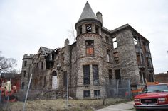 an old abandoned building with a red truck parked in front