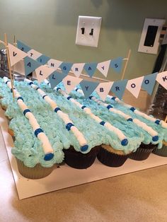 cupcakes with blue frosting are arranged on a table