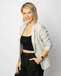 a woman in black top and grey jacket posing for a photo with her hands on her hips