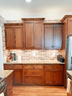 a kitchen with wooden cabinets and granite counter tops, along with a brick backsplash