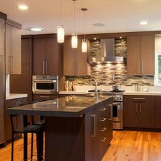 a large kitchen with wooden floors and stainless steel appliances, along with dark wood cabinets