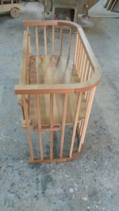 a wooden baby crib sitting on top of a cement floor