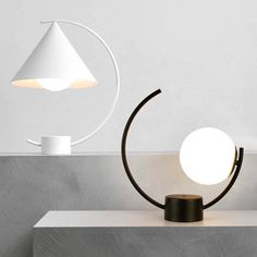 a table lamp sitting on top of a white counter next to a cup and saucer