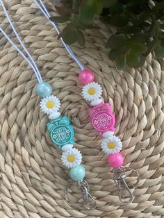 three necklaces with flowers on them sitting next to a potted plant