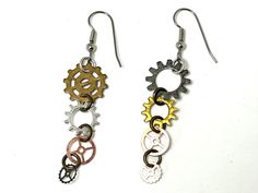 two pairs of earrings with gears hanging from the hooks on each earring, one in gold and silver