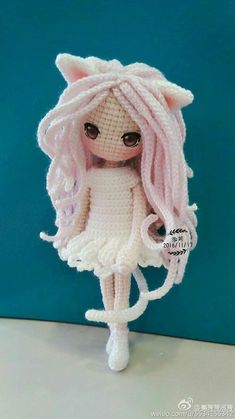 a crocheted doll with pink hair and big eyes wearing a white cat outfit