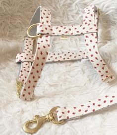 a white and red polka dot dog leash with gold hardware on a white furnishing