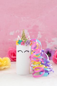 a white tube with a unicorn face and rainbow streamers on it next to flowers