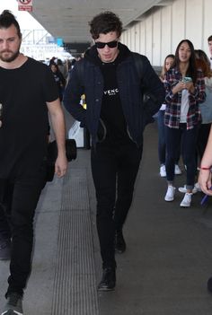 two young men walking through an airport carrying luggage