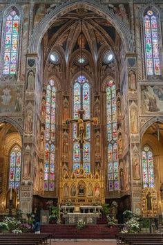 the inside of a church with stained glass windows and pews in front of it