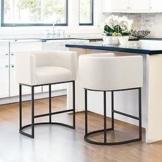 two white stools sitting in front of a kitchen island