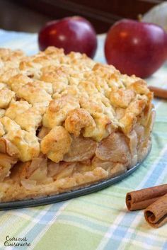 an apple pie on a table with cinnamon sticks