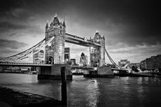 black and white photograph of the tower bridge in london, england taken on a cloudy day