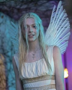 a woman with white hair and angel wings standing in front of a blue light background