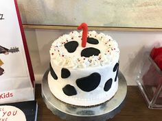 a birthday cake sitting on top of a table next to a book and some stuffed animals