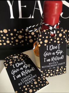 two black and gold gift tags with a red candle in it on a white table