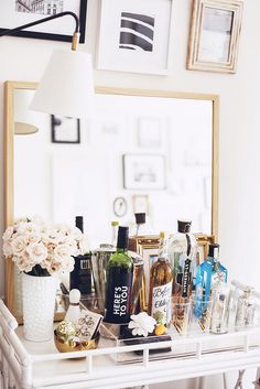 a white table topped with lots of bottles and vases next to a large mirror