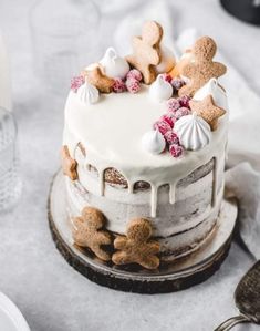 a cake with white frosting and gingerbreads on top sitting on a table