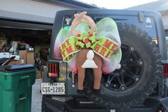 a large christmas decoration on the back of a jeep in front of a garage door