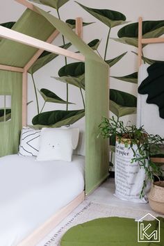 a bed with green leaves painted on the wall next to a potted plant and rug