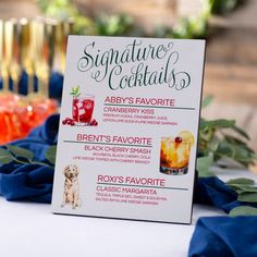 there is a sign that says signature cocktails on the table with blue napkins