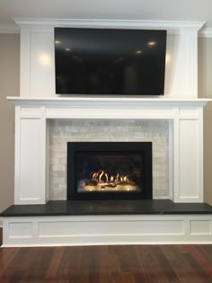 a fireplace with a flat screen tv above it and wood flooring in the room