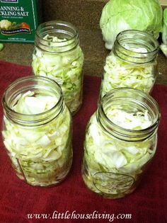 four jars filled with cabbage sitting on top of a red mat next to some vegetables