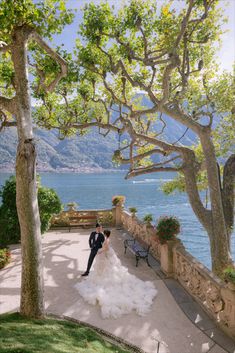 a bride and groom standing in front of the water