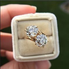 a person holding an engagement ring with three diamonds on it in a box that is open to show the inside