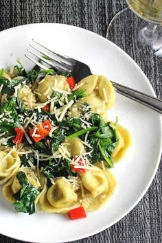 a white plate topped with pasta and spinach