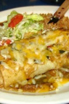 a white plate topped with chicken covered in cheese and sauce next to a side salad