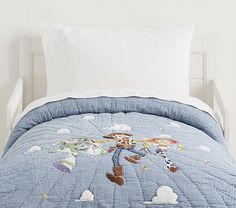 a child's bed with a blue quilted comforter and white pillow cases