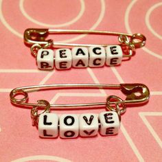 two bracelets with words that say peace and love on them sitting on a pink surface