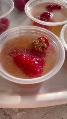 three plastic cups filled with liquid and some berries on top of each cup are sitting on a tray