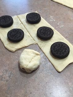 four oreo cookies sitting on top of a piece of dough next to an uncooked cookie