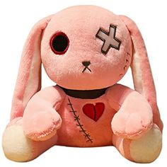 a pink stuffed animal with cross on it's chest and eyes sitting next to a white background