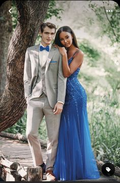 a man in a tuxedo and a woman in a blue dress standing next to each other